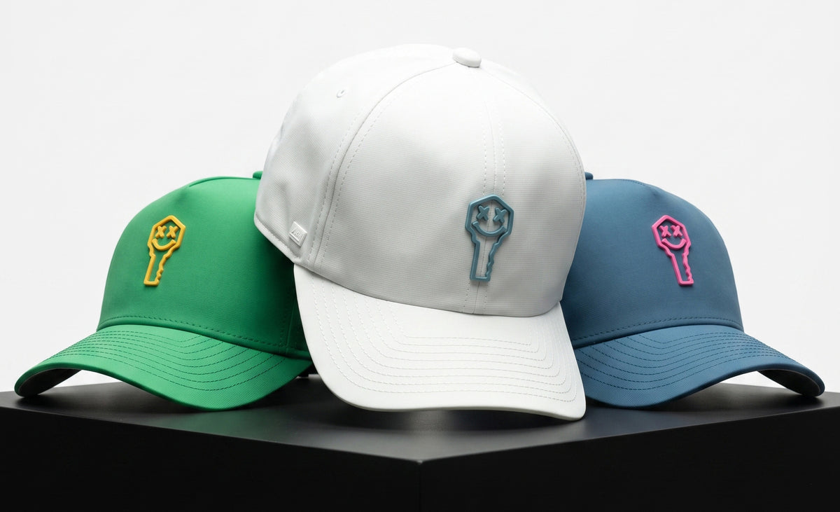 Key x Suay hats in green, white, and blue on a black pedestal